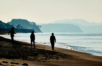 Rear view of people on beach against sky