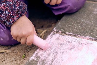 Close-up of hands holding purple while sitting outdoors