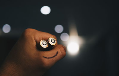 Cropped hand of person holding batteries with smiley face