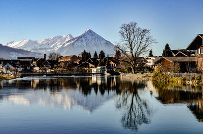 Scenic view of lake by houses against sky during winter