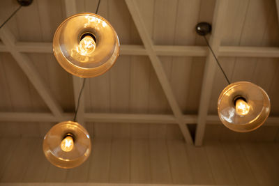 Low angle view of illuminated light bulb hanging on ceiling