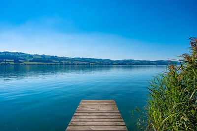 Pier over lake against blue sky