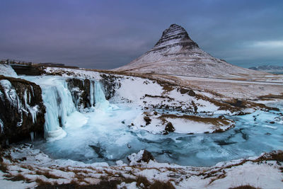 Scenic view of frozen waterfall and mountain against sky