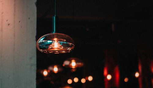 Low angle view of illuminated light bulb hanging on ceiling