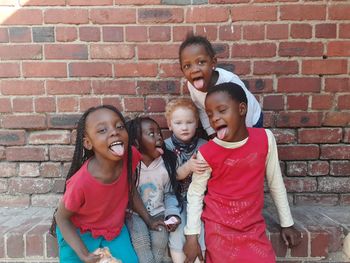 Portrait of a smiling girl against brick wall