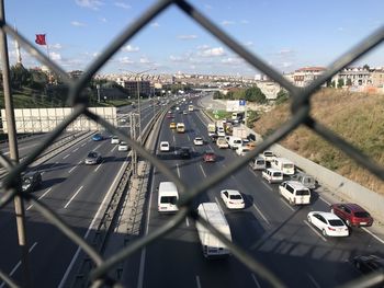 High angle view of traffic on highway seen through chainlink fence