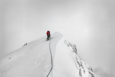 Low angle view of person walking on snowcapped mountain against sky