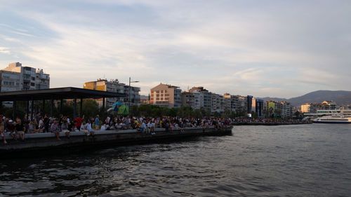 Boats in river in city against sky