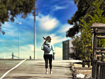 Full length rear view of woman standing against sky