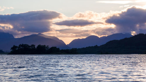 Scenic view of lake by silhouette mountains against sky