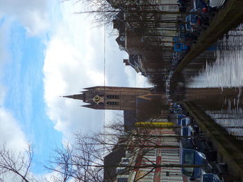 Bridge over river by buildings in city against sky