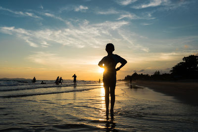 Silhouette man standing on beach against sky during sunset