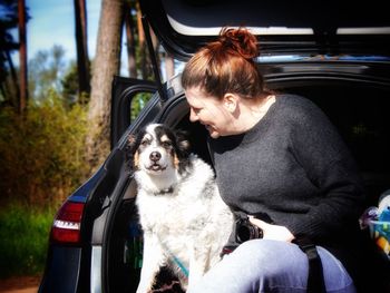 Woman with dog sitting in car