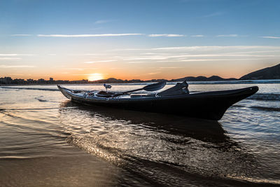 Boats in sea at sunset