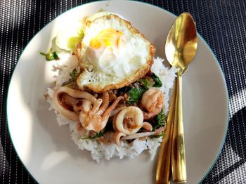 Rice topped with stir-fried seafood and basil fried egg