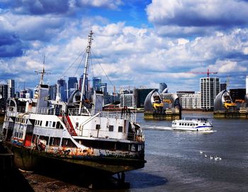 Ship moored on harbor by buildings in city against sky