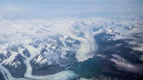 Aerial view of snowcapped mountains and sea against sky