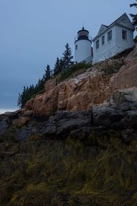 Low angle view of lighthouse by buildings against sky