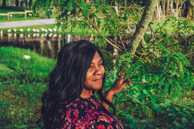 Portrait of smiling woman standing by plants