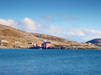 Traditional red white building in small port, coastline of cold north sea, norway.