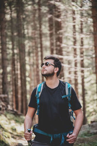 Young man looking away standing in forest