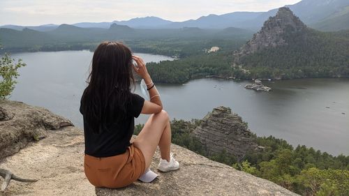 Rear view of woman looking at lake against mountain