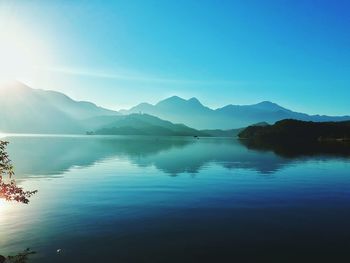 Scenic view of lake and mountains against clear blue sky