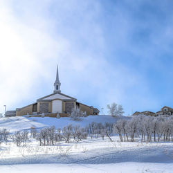 Church on field by building against sky