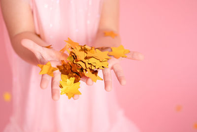 Close up of child hands with gold confetti. kid in pink dress celebrating birthday