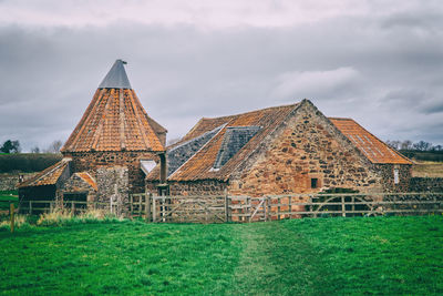 Old mill on field against sky