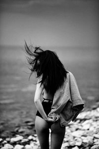 Midsection of woman standing at beach against sky