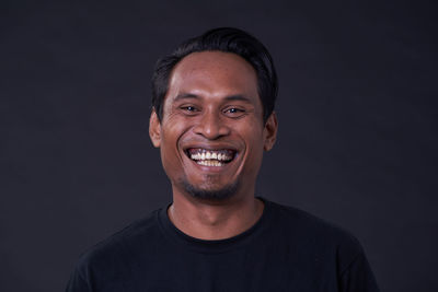 Portrait of a smiling young man against black background