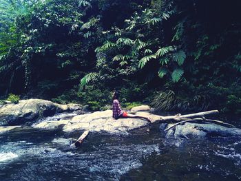 Woman sitting on rock in forest