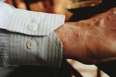 Cropped hand of man wearing shirt at home