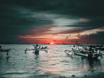 Silhouette boats in sea against sky during sunset