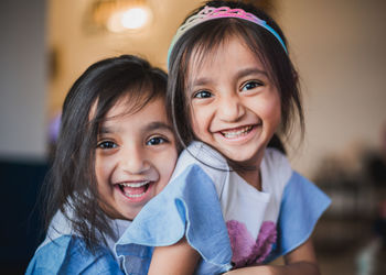 Portrait of cheerful sisters embracing