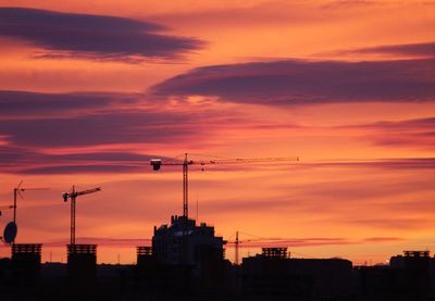 Silhouette of buildings against dramatic sky during sunset