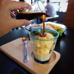 Close-up of hand holding drink on table