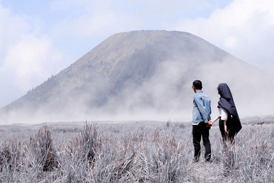 Rear view of men standing on landscape against sky