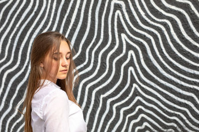 Thoughtful young woman standing against graffiti wall