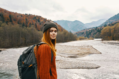 Portrait of young woman standing on mountain against sky