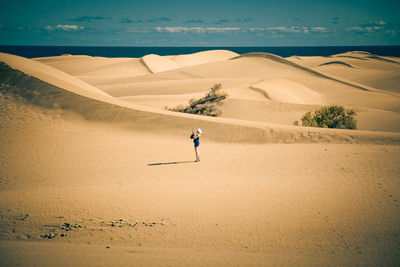 View of woman in sand dunes against sky