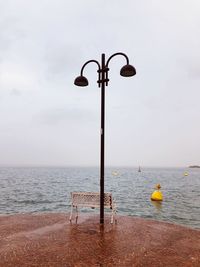 Street light by sea against sky