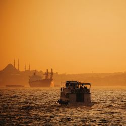 Ship sailing on sea against clear sky during sunset