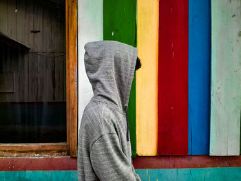 Side view of person standing against multi colored wall