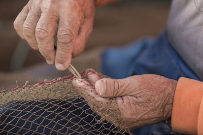 Midsection of man making net