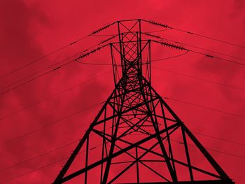 Low angle view of silhouette electricity pylon against sky