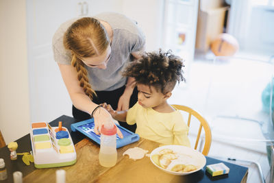 Rear view of mother and daughter sitting on table