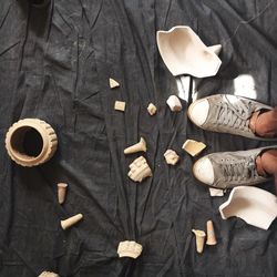 Low section of man standing by broken ceramic pot on black fabric