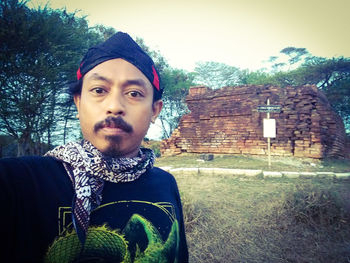 Portrait of young man standing against building